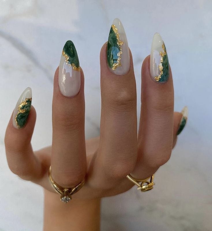 Mão branca com anéis e unha verde com dourado