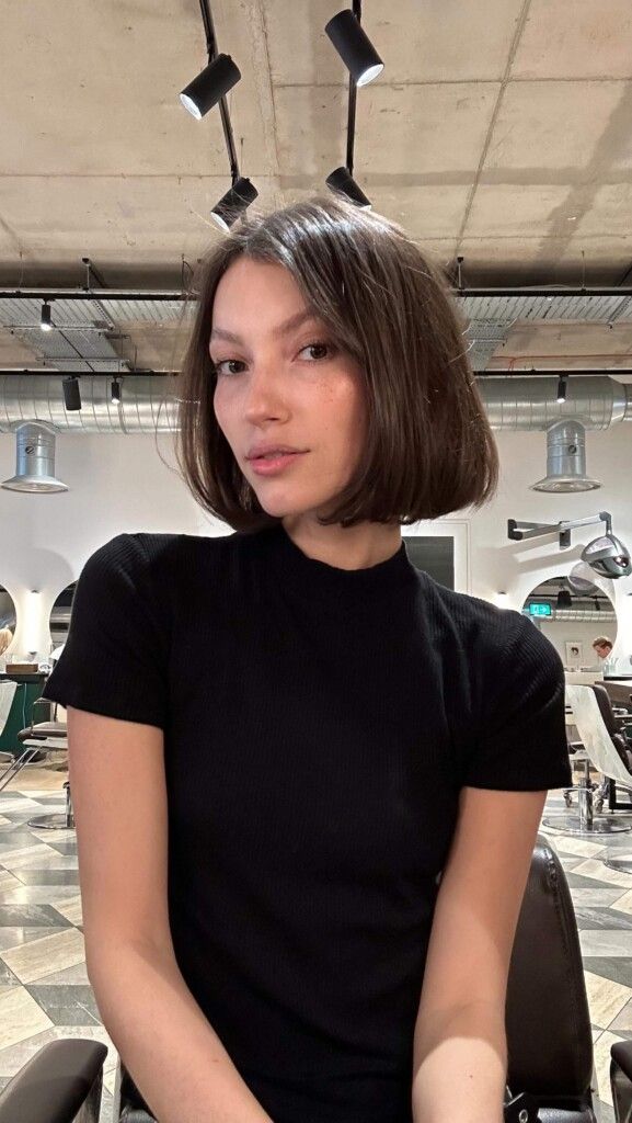 Mulher branca, com cabelo castanho, curto e escovado, no estilo bubble bob, com franja média