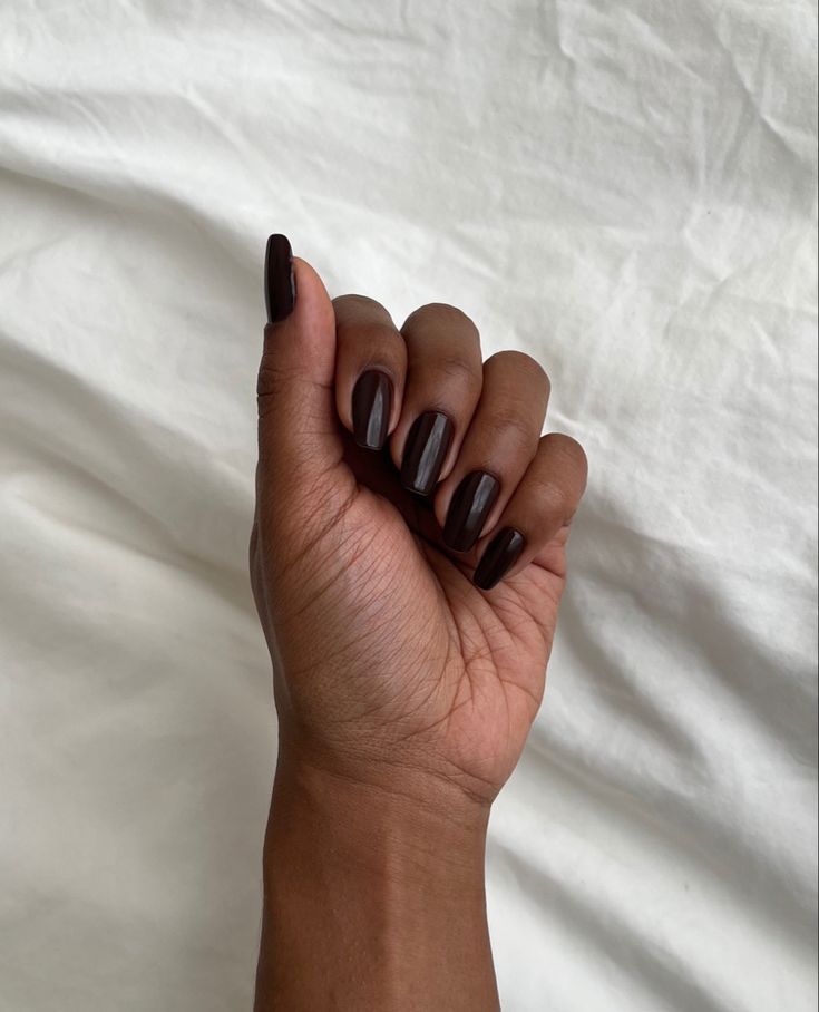 Mão negra fechada com a unha marrom escuro