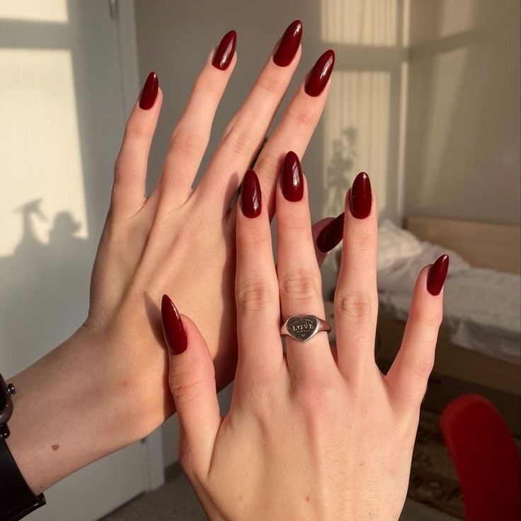 Mãos brancas com anel e unha com esmalte vermelho cereja