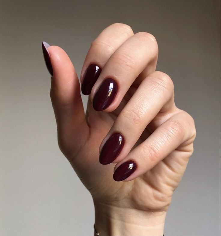 Mão branca curvada com unha vermelho vinho