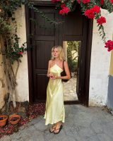 Linda SZA. Ela usa vestido amarelo manteiga de cetim e chinelo preto slim da Havaianas