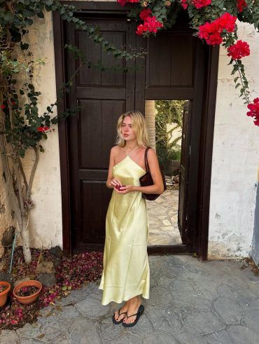 Linda SZA. Ela usa vestido amarelo manteiga de cetim e chinelo preto slim da Havaianas