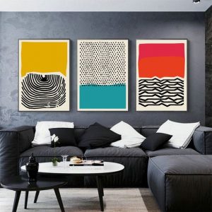 Sofá e parede em tons de cinza com quadros coloridos abstratos