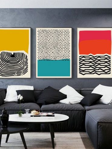 Sofá e parede em tons de cinza com quadros coloridos abstratos