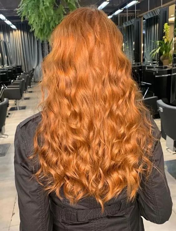 Mulher de costas com cabelo ruivo dourado cacheado