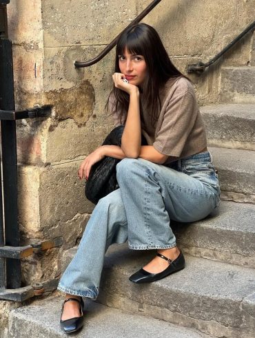 Mulher branca com franja, blusa de malha, calça jeans e sapatilha de bailarina
