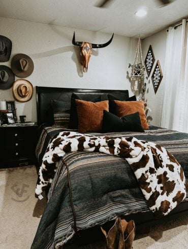 Quarto de casal com chapéus pendurados na parede, cabeça de boi na cabeceira