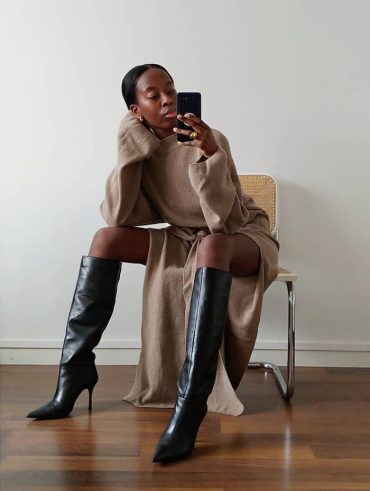 Sylvie Mus. Ela usa vestido nude com bota preta de cano longo