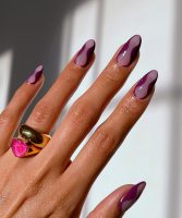 Mão branca com anéis e unha amendoada com decoração lilás