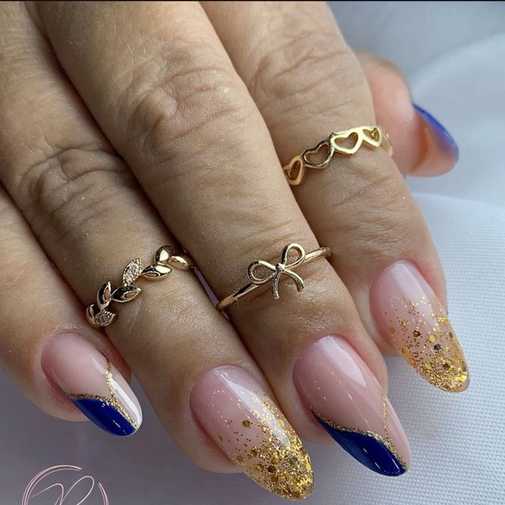 Mão branca com anéis e unhas azul com dourado