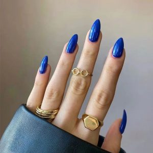 Mão branca com anéis dourados e unha azul klein