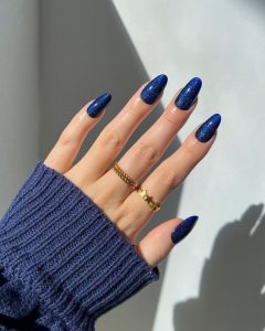 Mão branca com anéis e unha azul marinho brilhosa