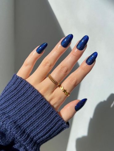 Mão branca com anéis e unha azul marinho brilhosa