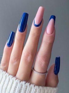 Mão branca com manga branca, anel e unha bailarina azul com francesinha normal e invertida