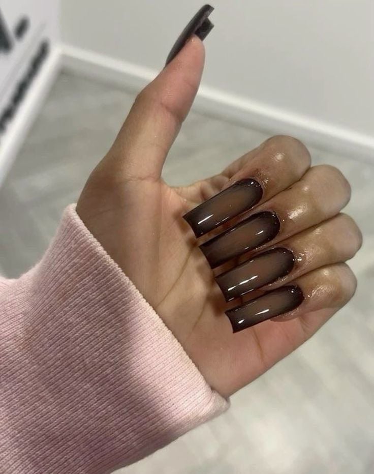Mão negra meio fechada com manga rosa, e unha bailarina marrom estilo aura