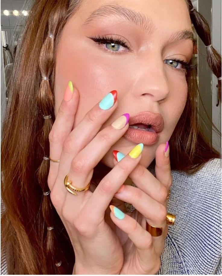 Gigi Hadid com a mãos apoiadas no rosto, unha colorida com francesinha colorida