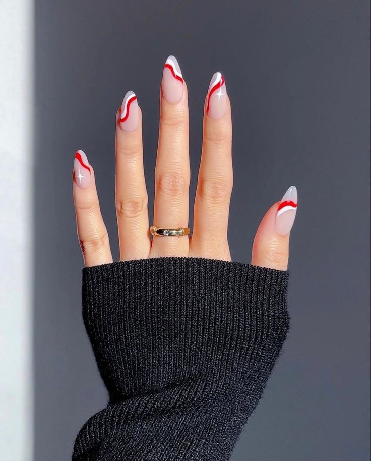 Mão branca reta com manga preta, anel e unha decorada vermelho e branco