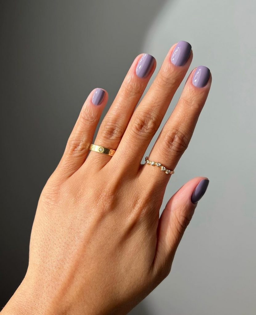 Mão branca com anéis e unha curta quadrada lilás