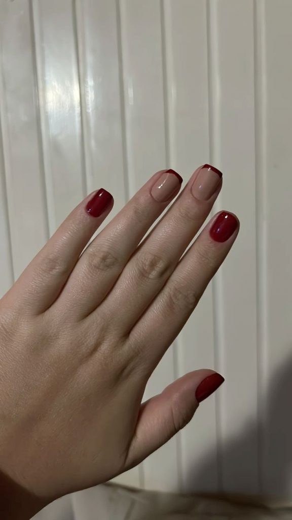 Mão branca com unha vermelha e nude com francesinha vermelha