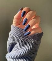 Mão branca curvada com manga azul e unha de gel azul
