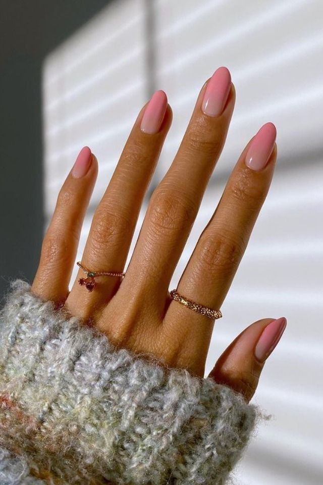 Mão branca com anéis e unha degradê rosa e branco