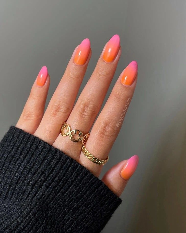 Mão branca com anéis e unha degradê rosa e laranja