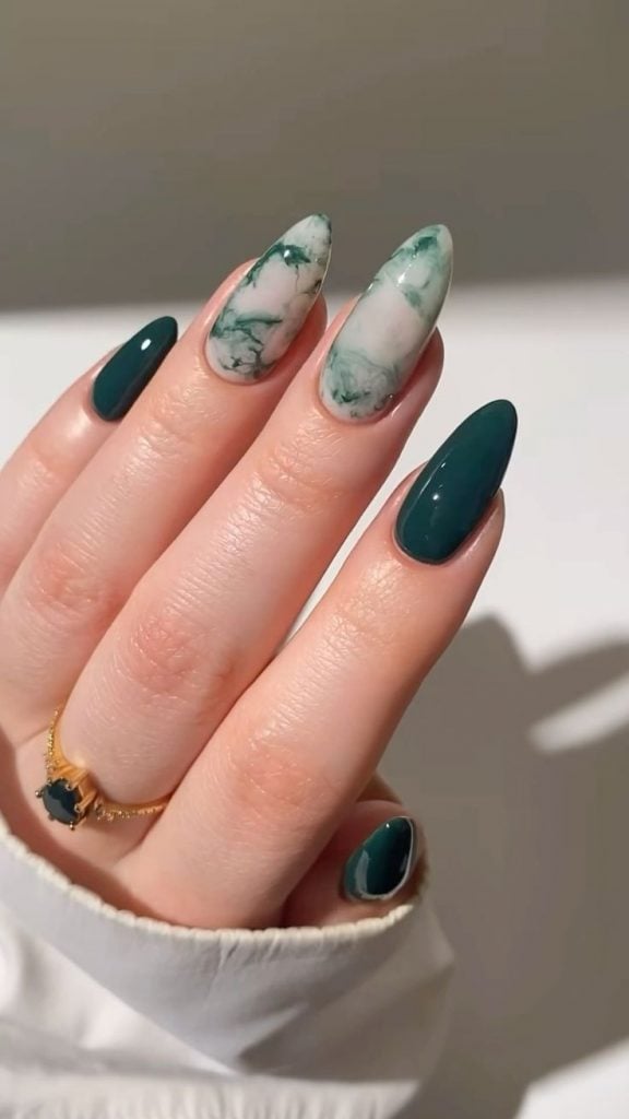 Mão branca com anel e unha verde esmeralda com marmorizado