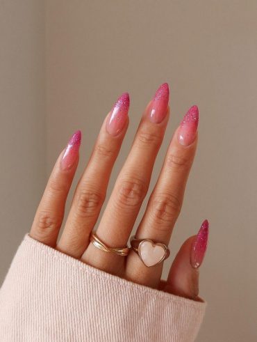 Mão branca com anéis e unha rosa jelly com francesinha de brilho