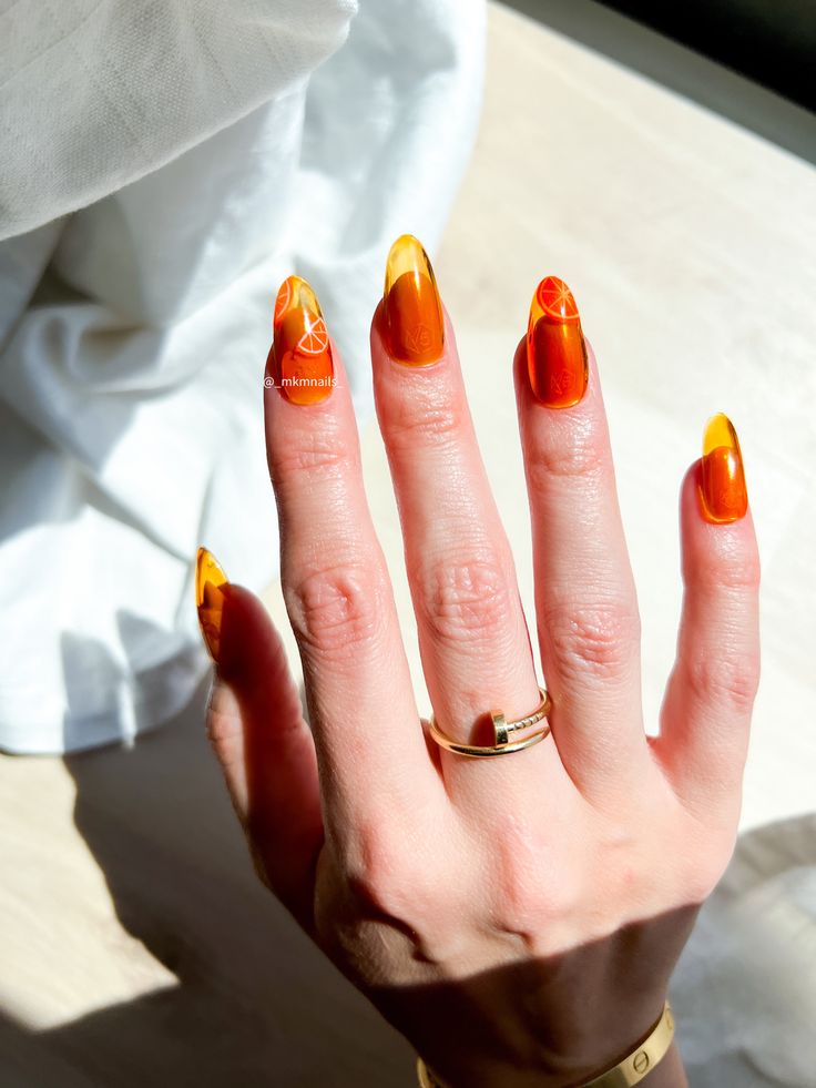Mão branca com anel e unha jelly laranja com laranjas