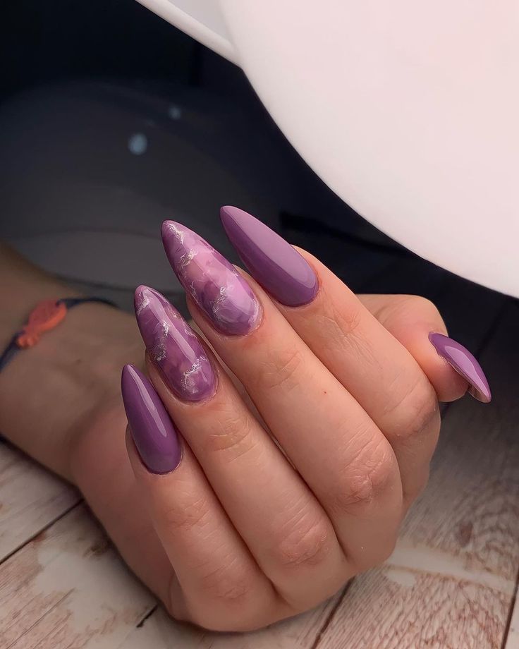 Mão branca curvada com unha stiletto lilás 