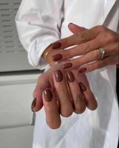 Mãos brancas com anel apoiadas e com unha marrom café