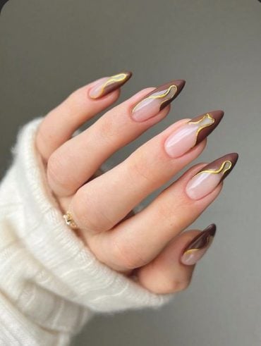 Mão branca curvada com unha marrom com dourado