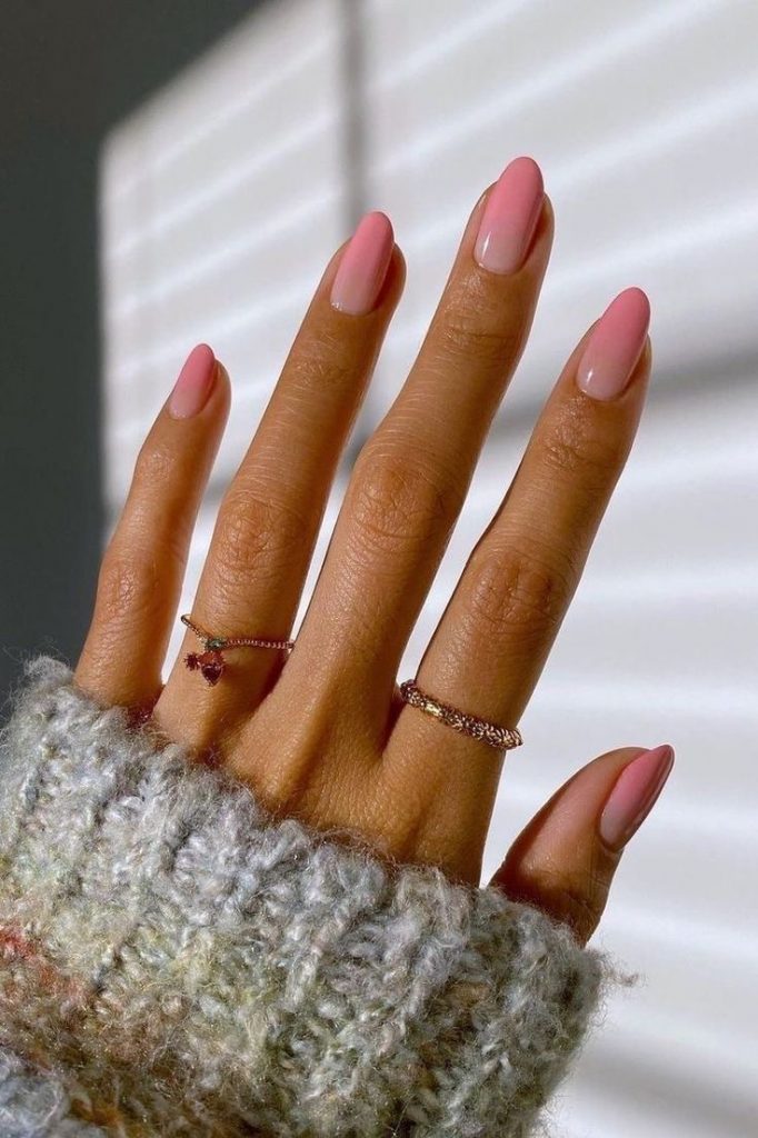 Mão branca com anéis e unha rosa claro degradê