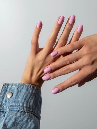 Mãos brancas com manga de jeans e unha curta rosa claro