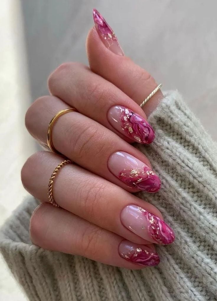 Mão branca com anéis fechada com unha rosa e dourado