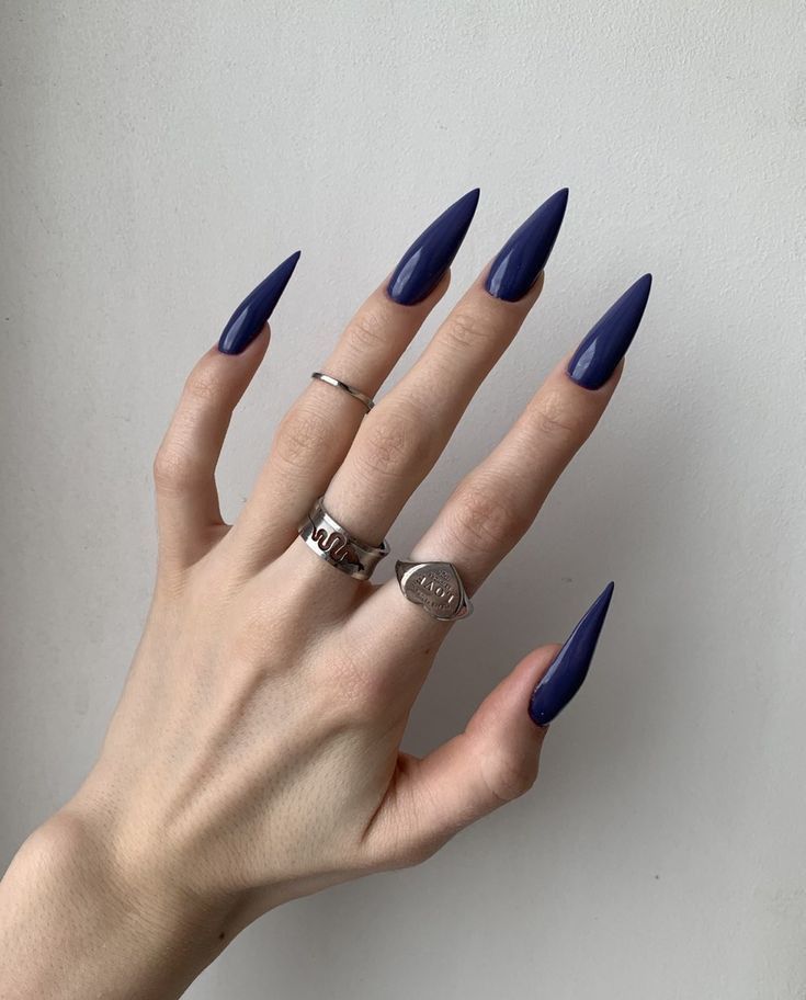 Mão branca com anéis e unha stiletto azul escuro