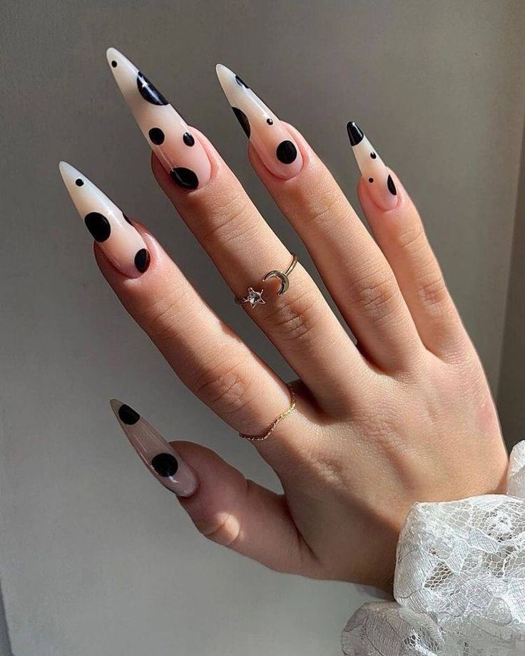 Mão branca com anéis e unha transparente com bolas pretas