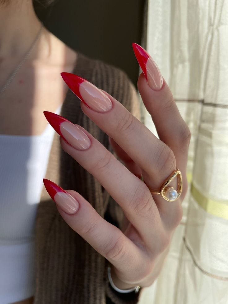 Mão branca com anel e unha stiletto francesinha vermelha