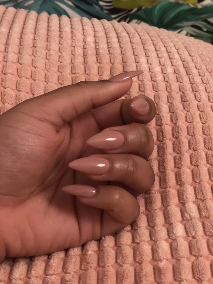 Mão branca curvada com unha stiletto nude
