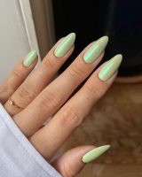 Mão branca com anel e unha verde claro perolada