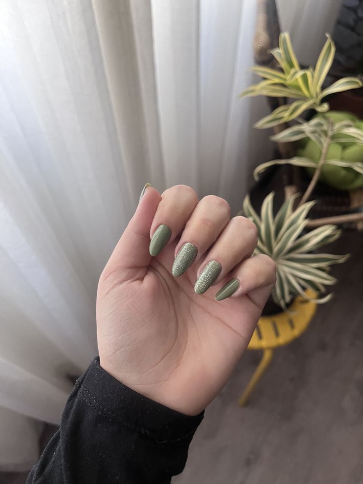 Mão branca curvada com unha verde militar com brilho