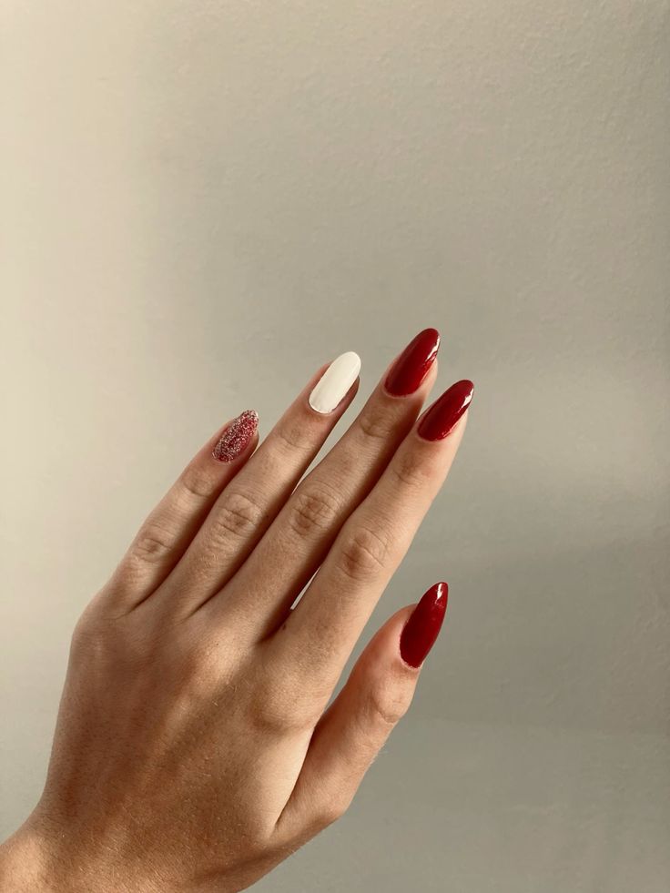 Mão branca com unha vermelha, branca e com glitter
