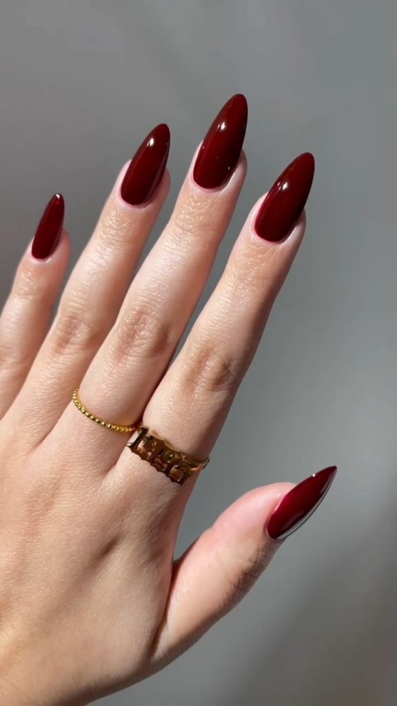 Mão branca com anel e unha vermelho cereja