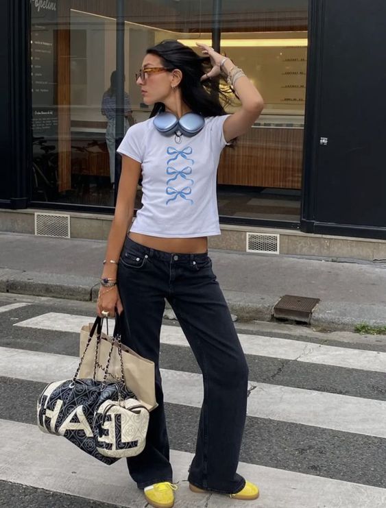 Mulher magra e alta usando baby tee branca com laços e calça jeans de cintura baixa