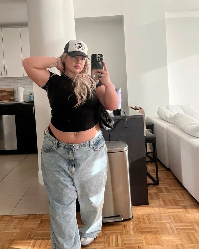 Mulher gorda usando calça jeans de lavagem clara e baby tee preta