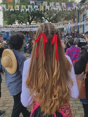 Cabelo longo e loiro com trança raiz e laços vermelhos