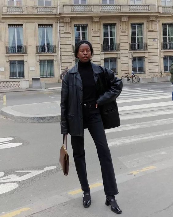 Mulher usando casaco de couro preto e calça jeans escura com sapato 