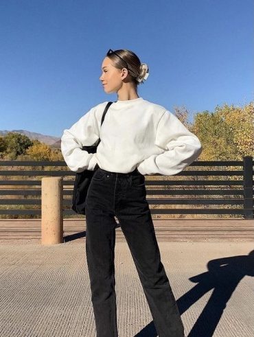 Mulher usando moletom branco e calça jeans escura com botas