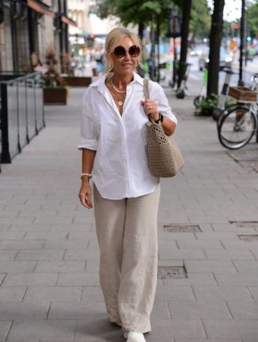 Mulher de 50 anos usando camisa brnca e calça caqui